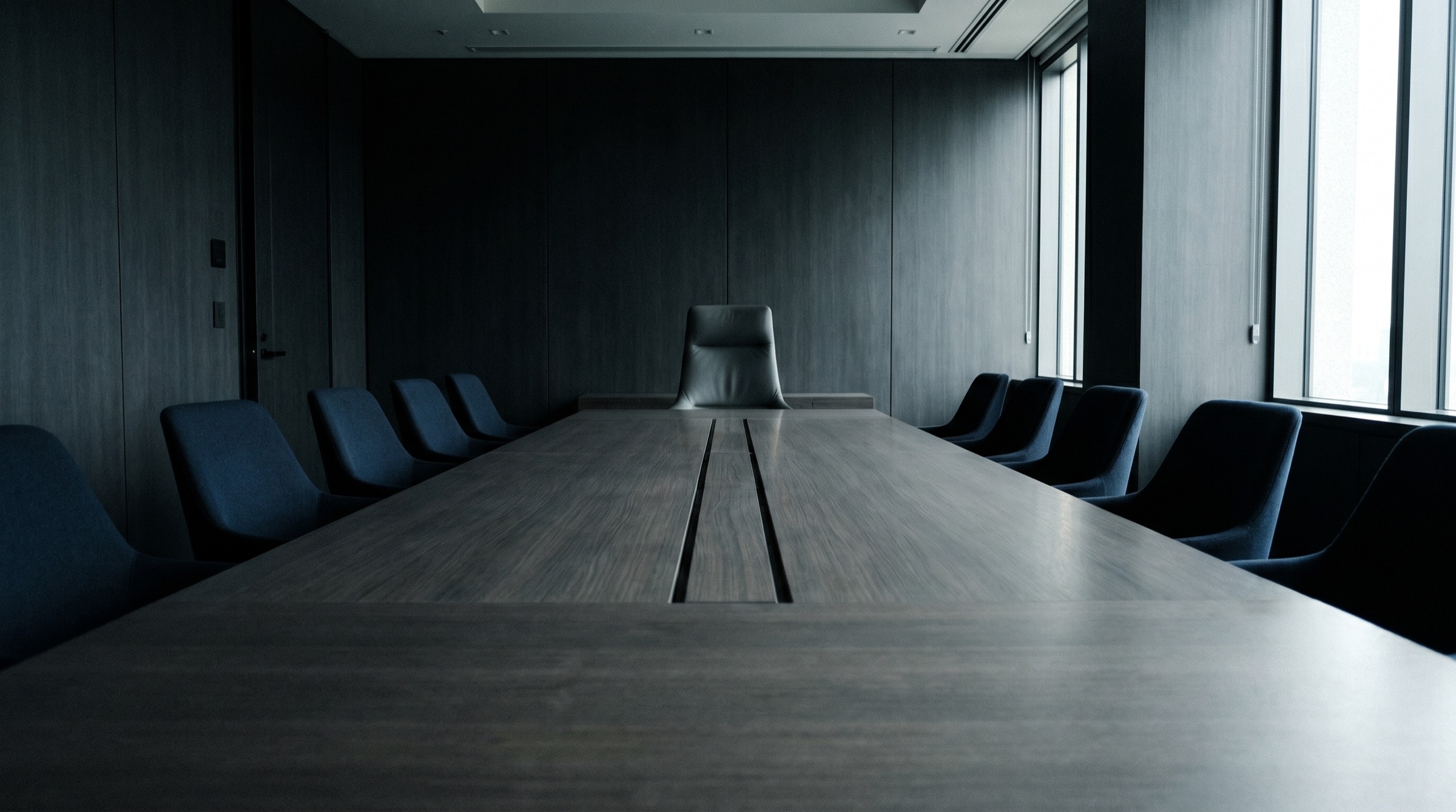 Langer, leerer Konferenztisch mit einem einzelnen Stuhl am Kopfende
